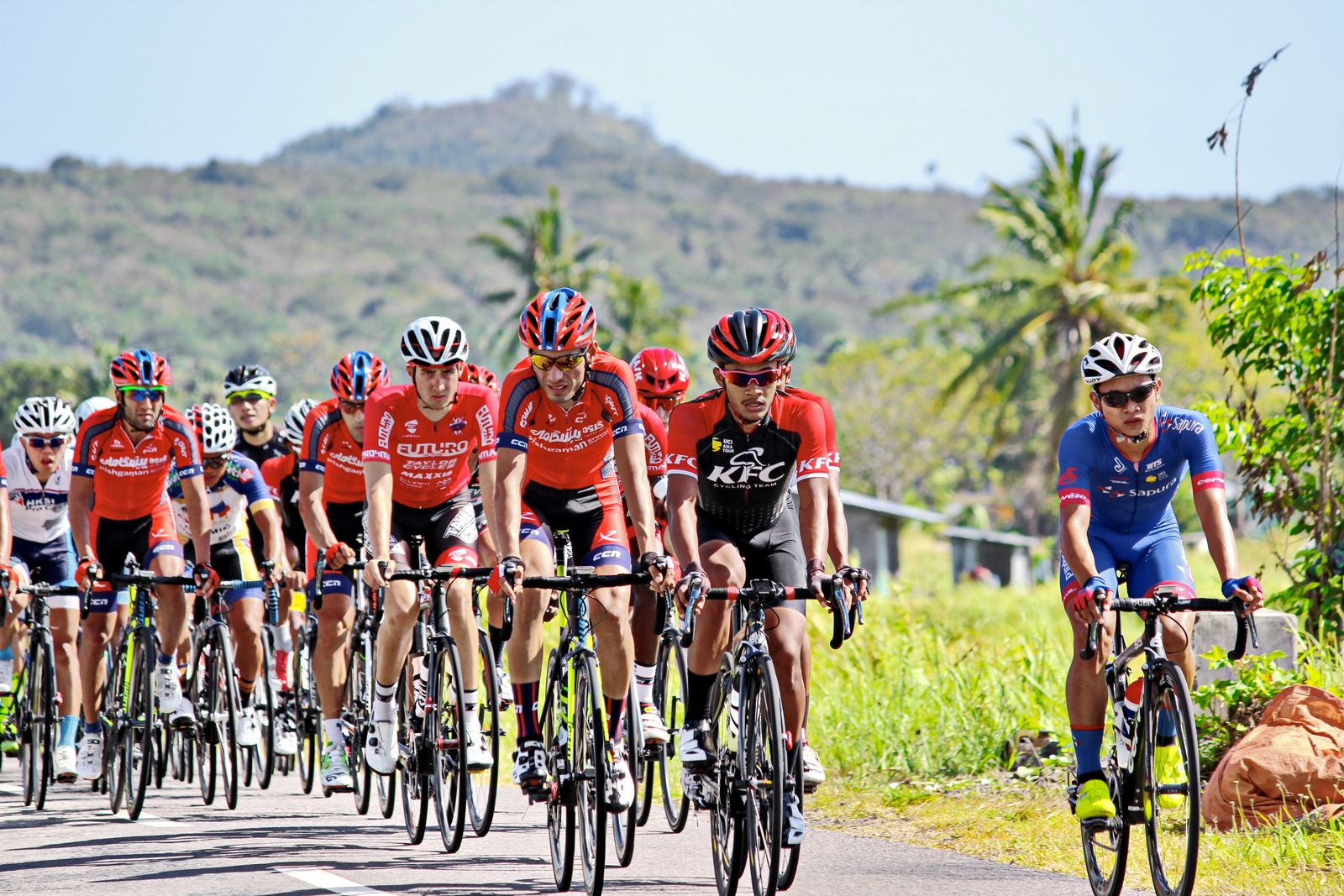 Racers in colourful team kit on a country road